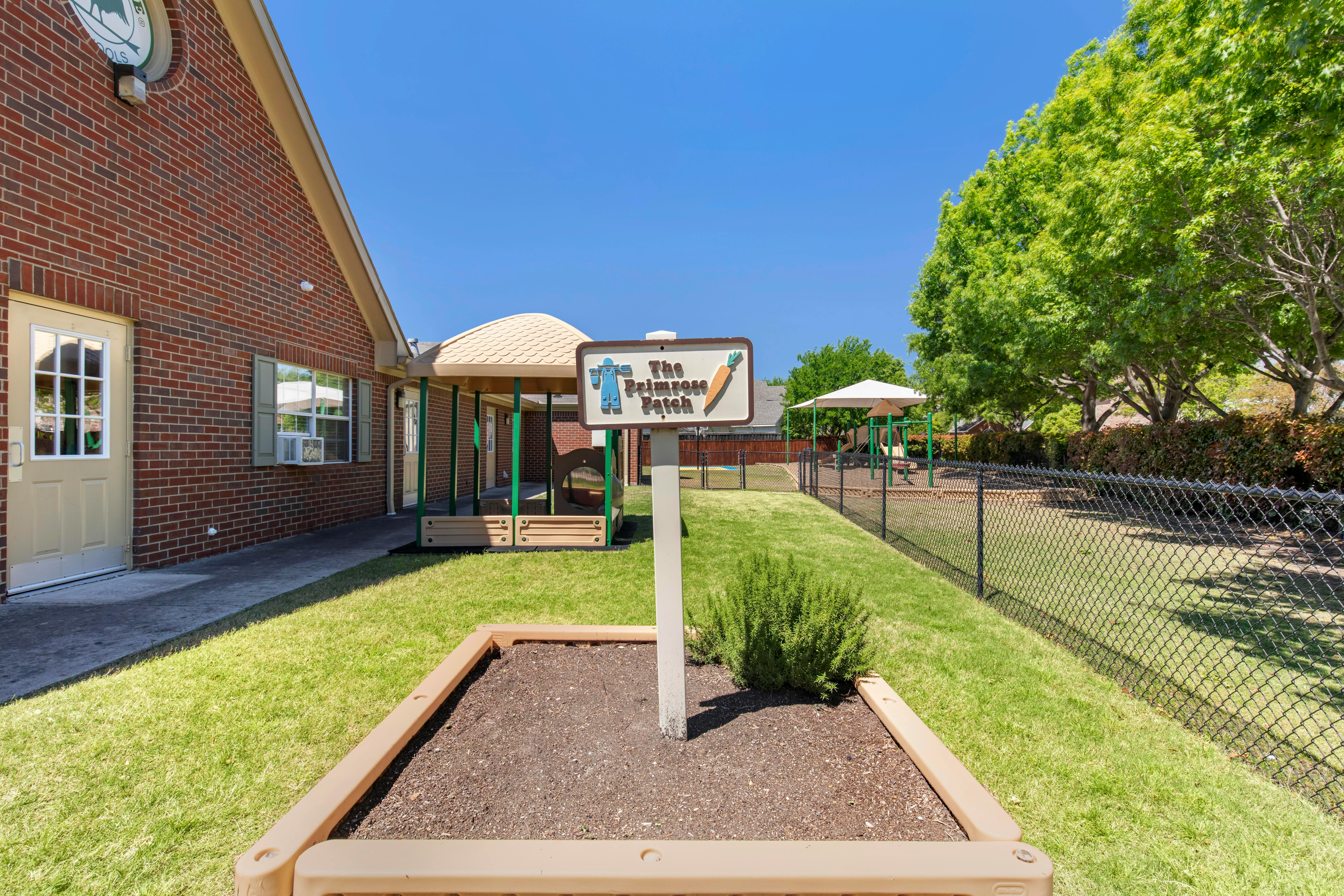 Sign for "The Primrose Patch" with a small play area and brick building