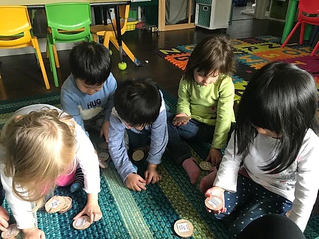 Children playing with small round objects on a rug