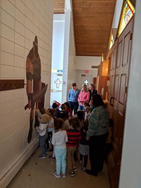 Children and adults looking at a wall decoration in a hallway