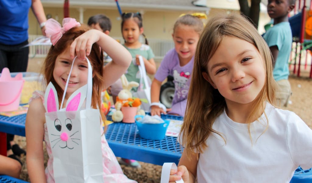 Two children holding bags with other children in the background