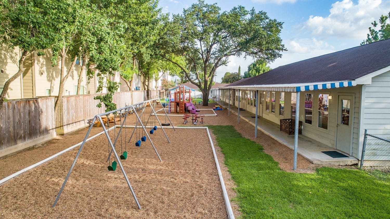 Outdoor playground with swings and a building with an awning