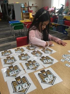 Child at a table with alphabet learning cards