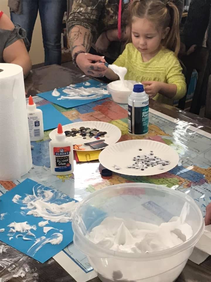 Child and adult making crafts with glue and googly eyes