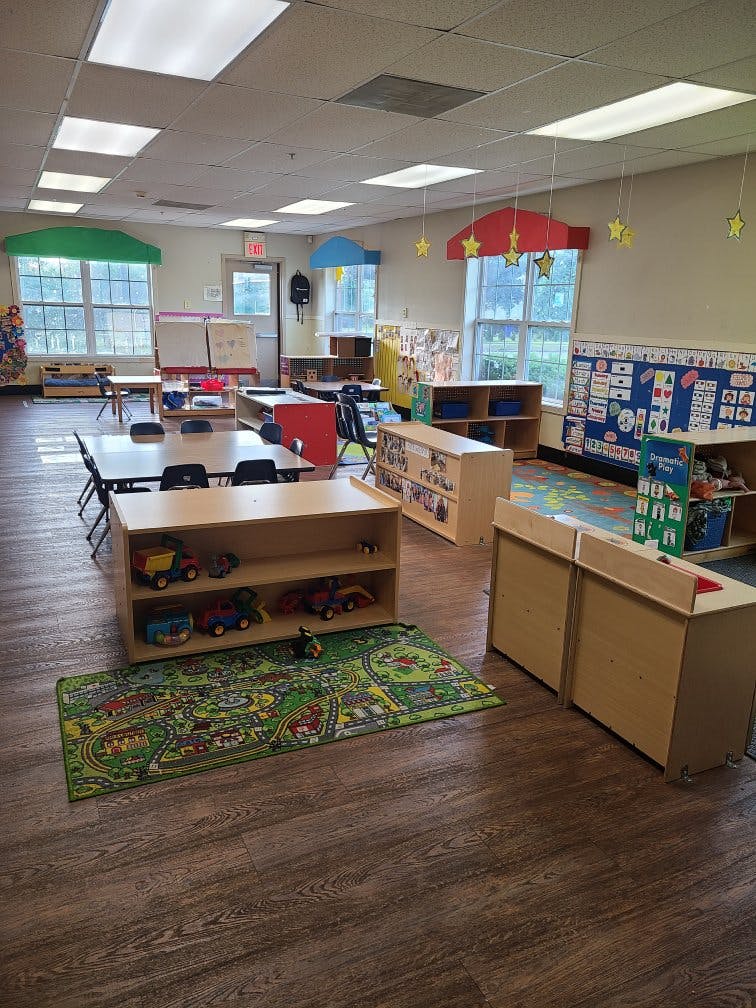 An empty early childhood classroom with multiple activity areas and small tables