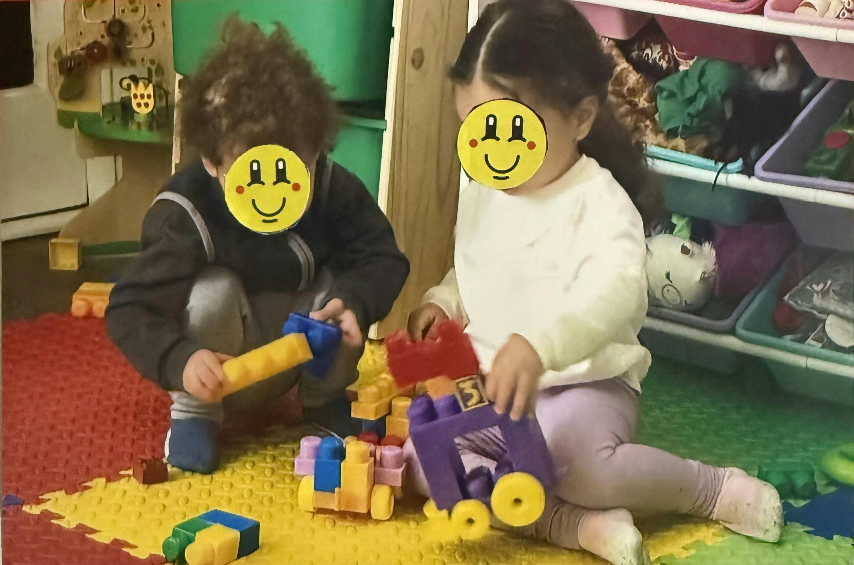 Two children playing with colorful building blocks on a mat