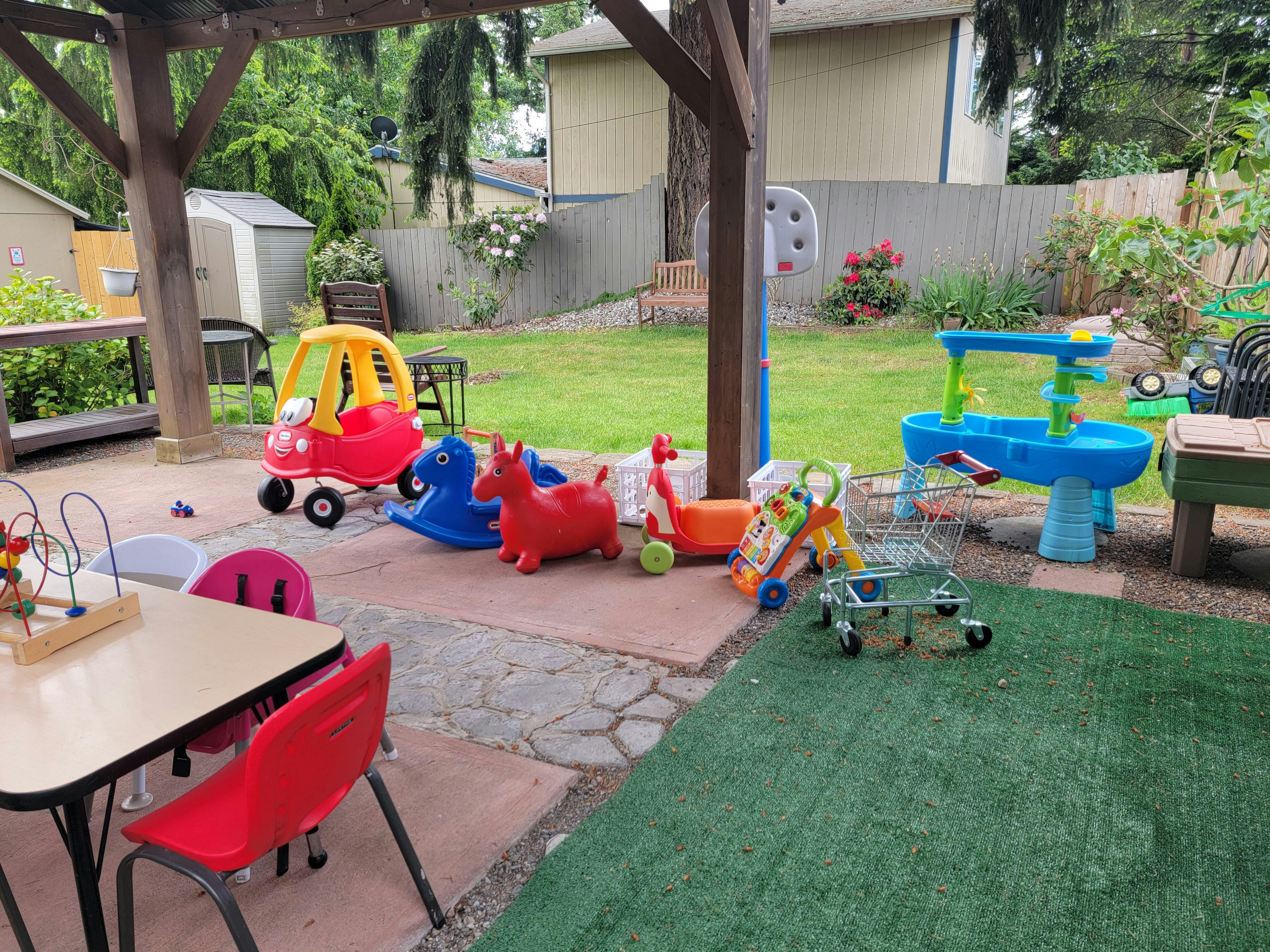 Outdoor play area with various children's toys on patio and grass