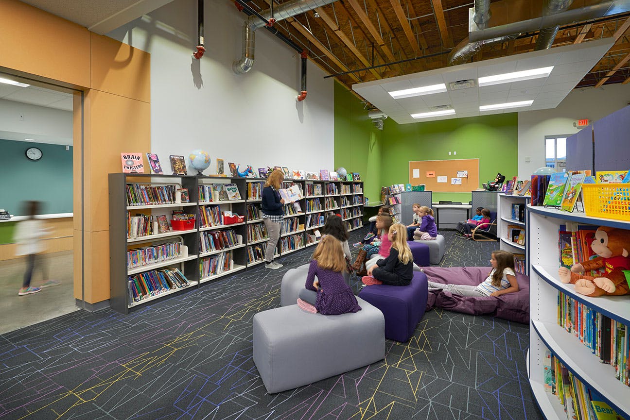 Children and adults in a library with bookshelves and seating
