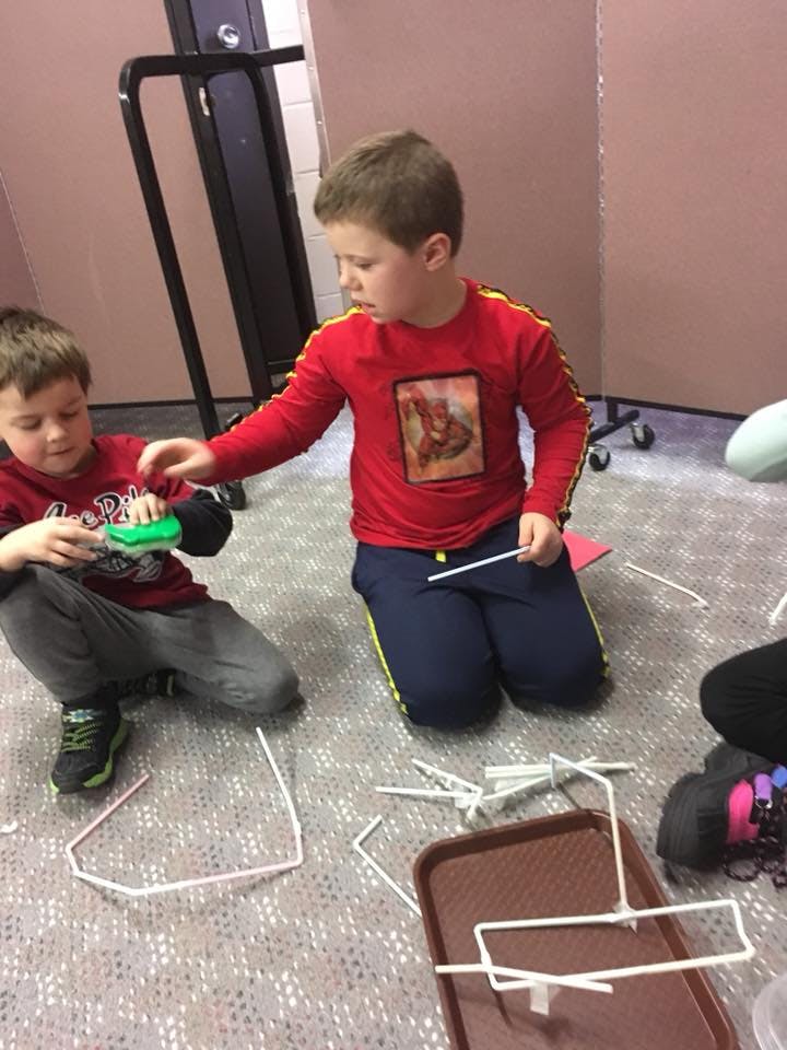 Two children on the floor playing with straws and connectors