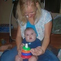 Person holding a child who is playing with a stacking toy