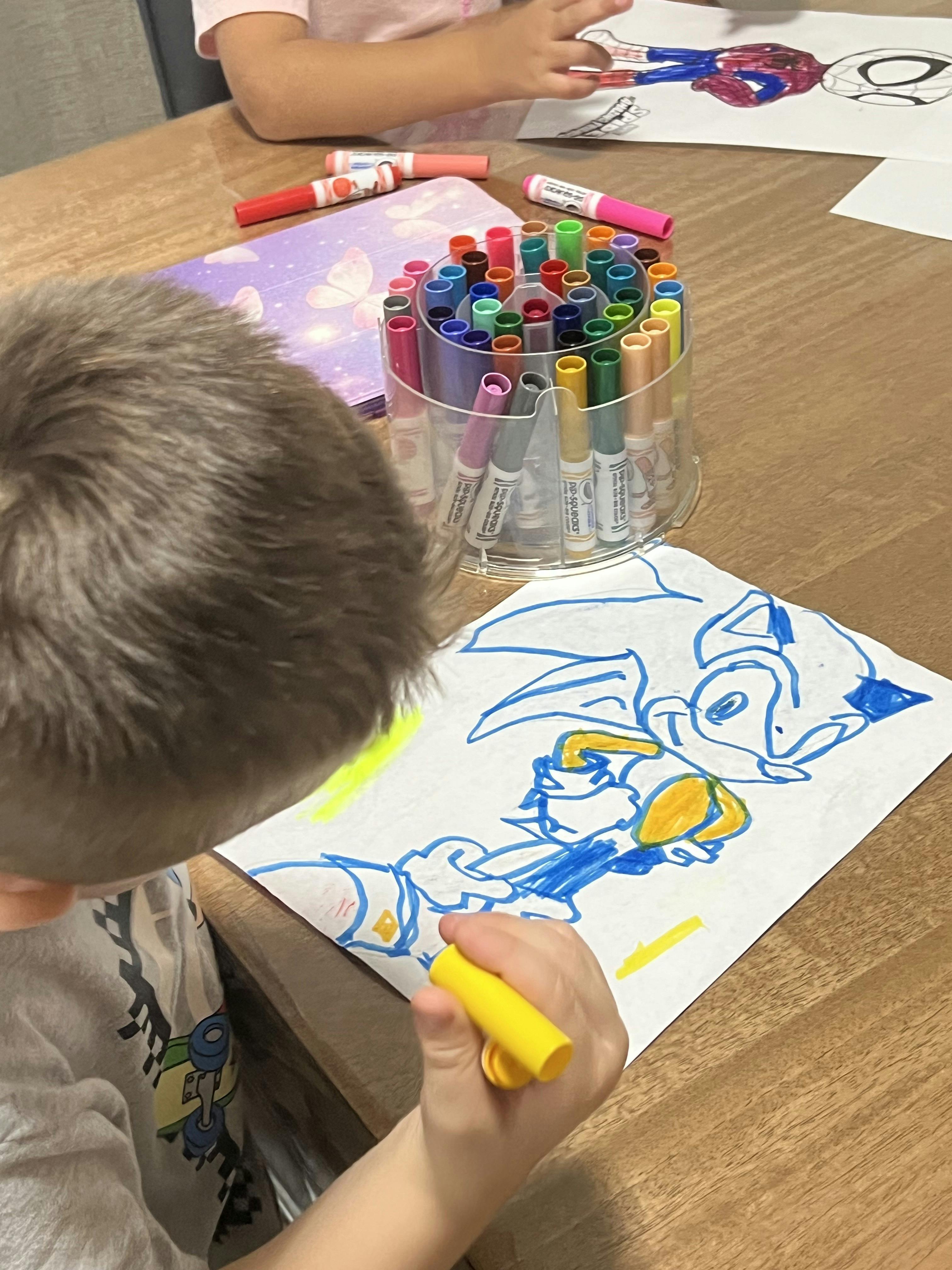 Child coloring a picture with a marker at a table