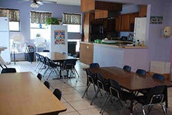 Dining area with multiple tables and chairs, kitchen in background