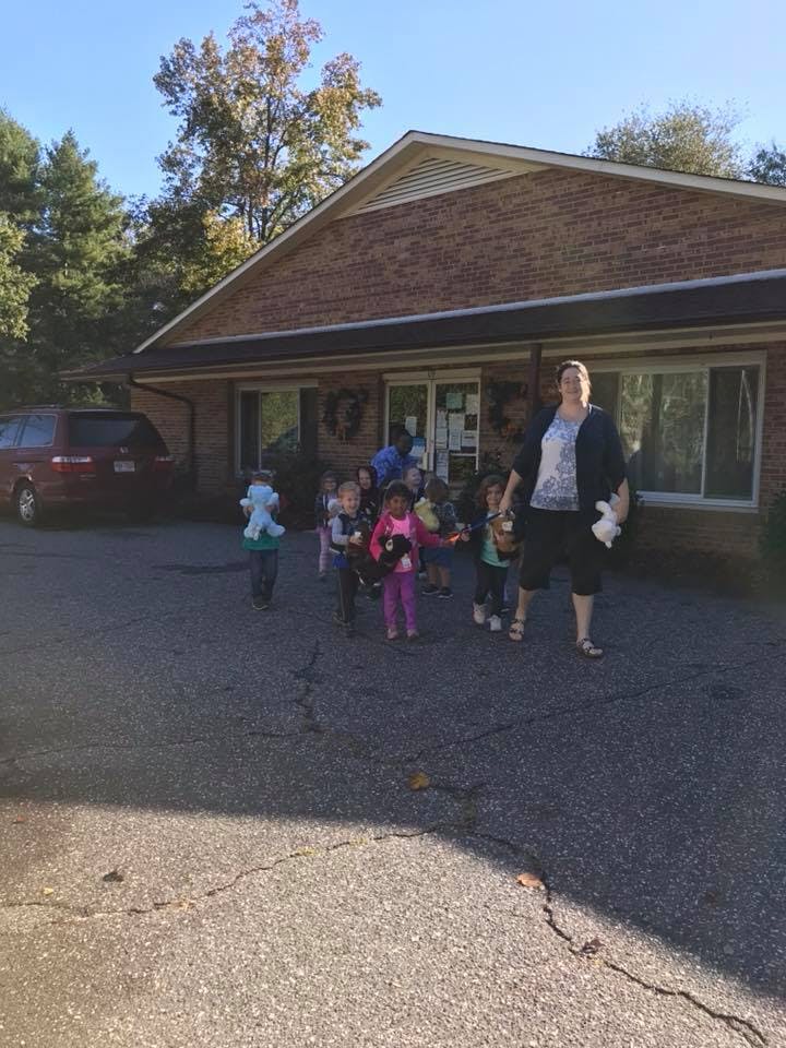 Adult and group of children walking outside a building