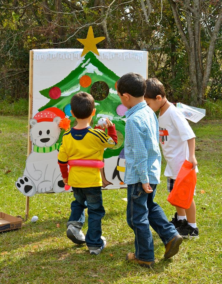 Three children playing a Christmas tree toss game outdoors