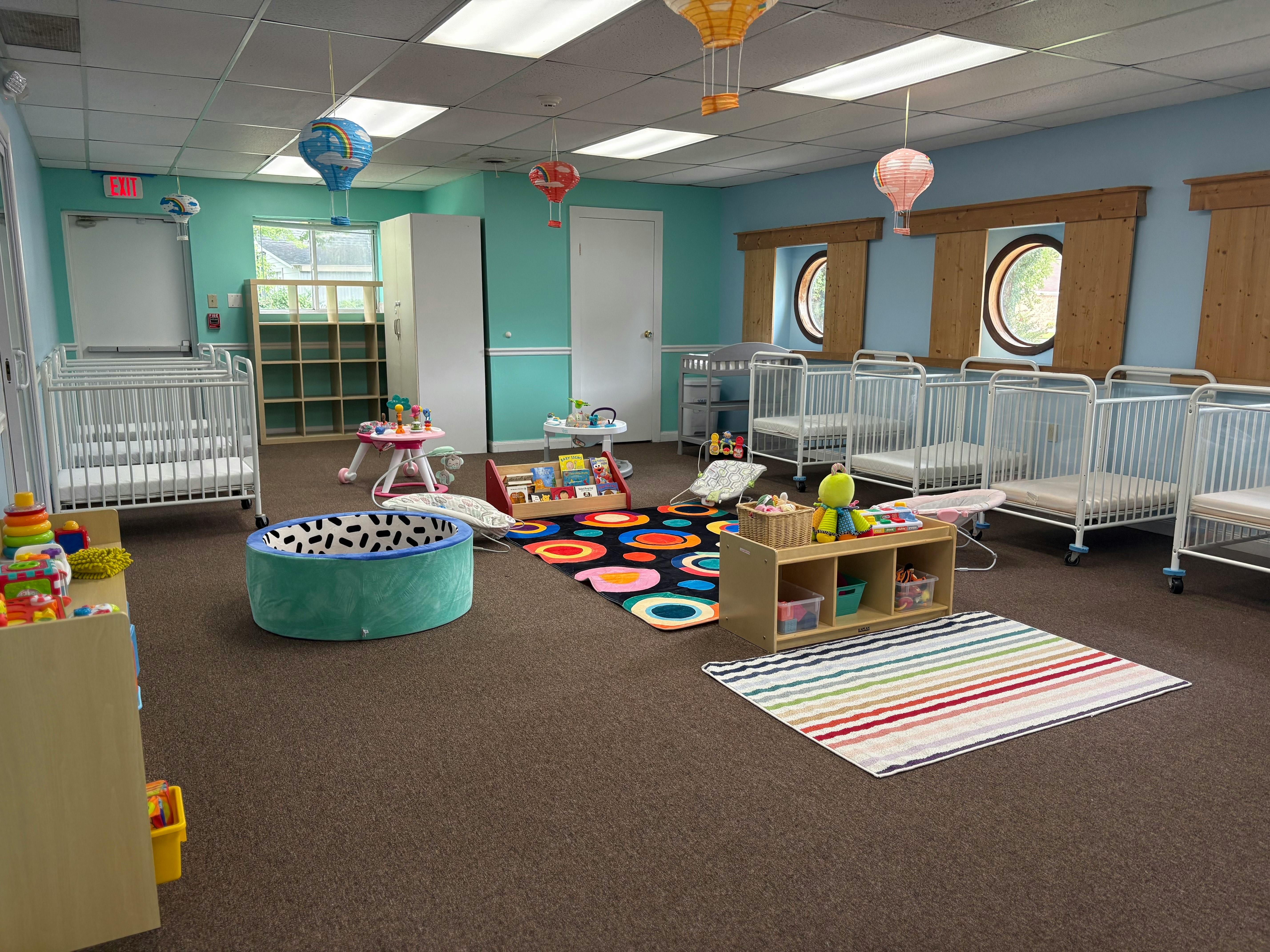 Daycare room with multiple cribs, play mats, and toys