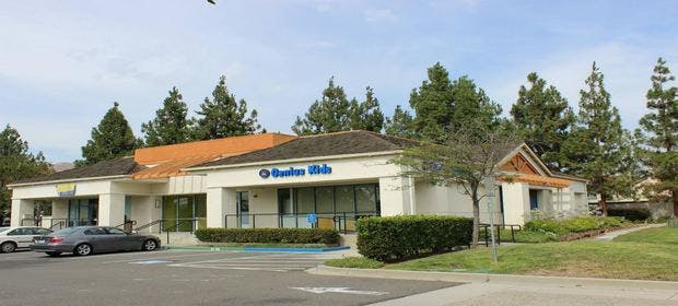 Building with "Bank of America" sign and parked cars
