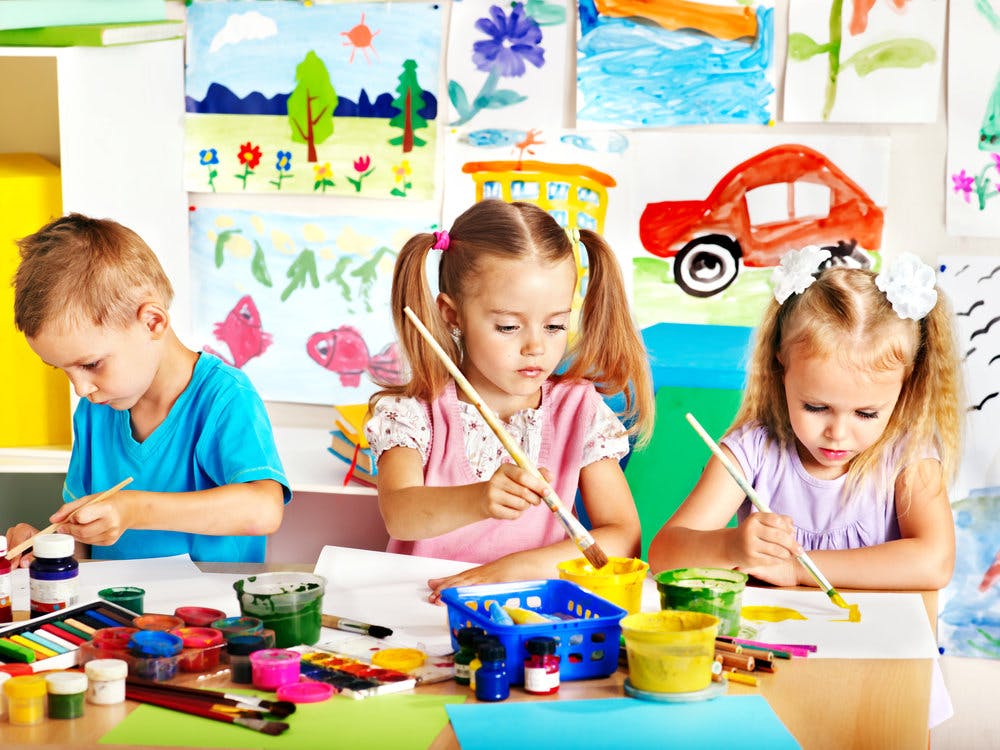 Three children painting at a table