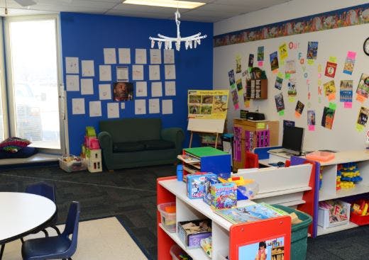 Classroom with blue and white walls, children's artwork, and colorful shelves