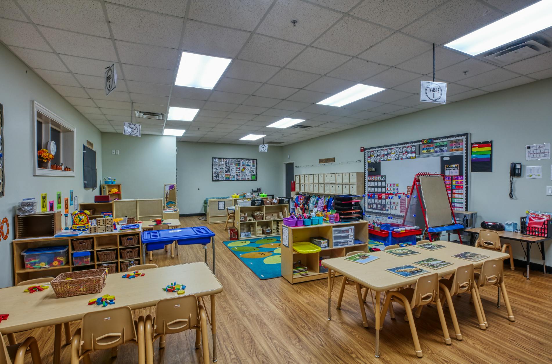 A colorful and organized classroom for young children with small tables and chairs