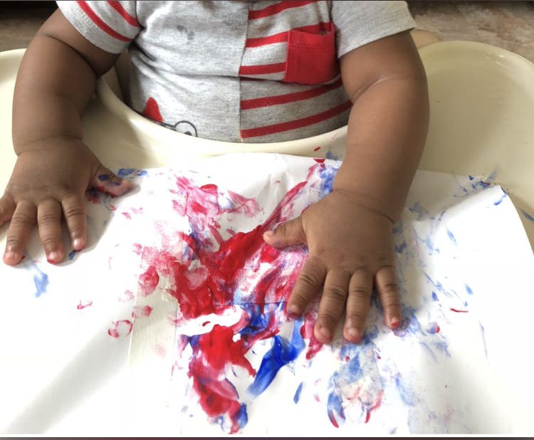 Child's hands on paper with red and blue paint