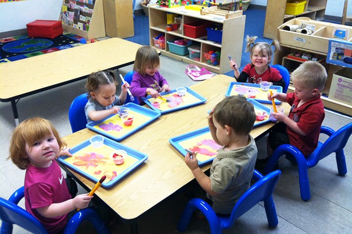 Children painting at a table in a classroom