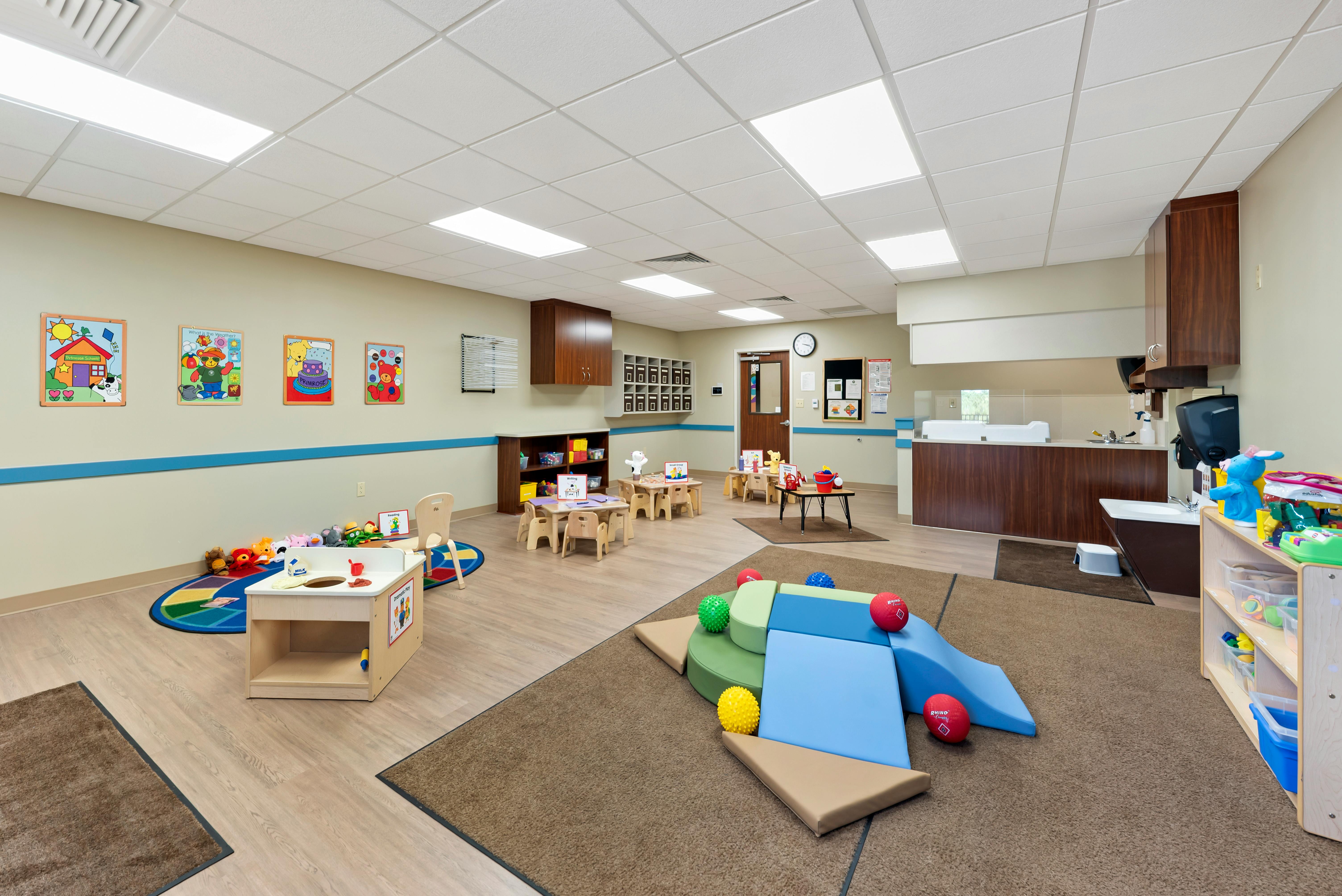 Empty colorful children's play room with small tables, chairs, and soft play equipment