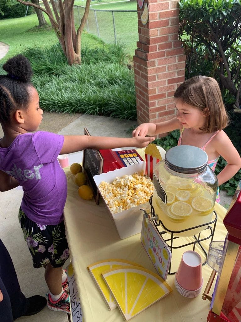 Two children interacting at a table with popcorn and lemonade