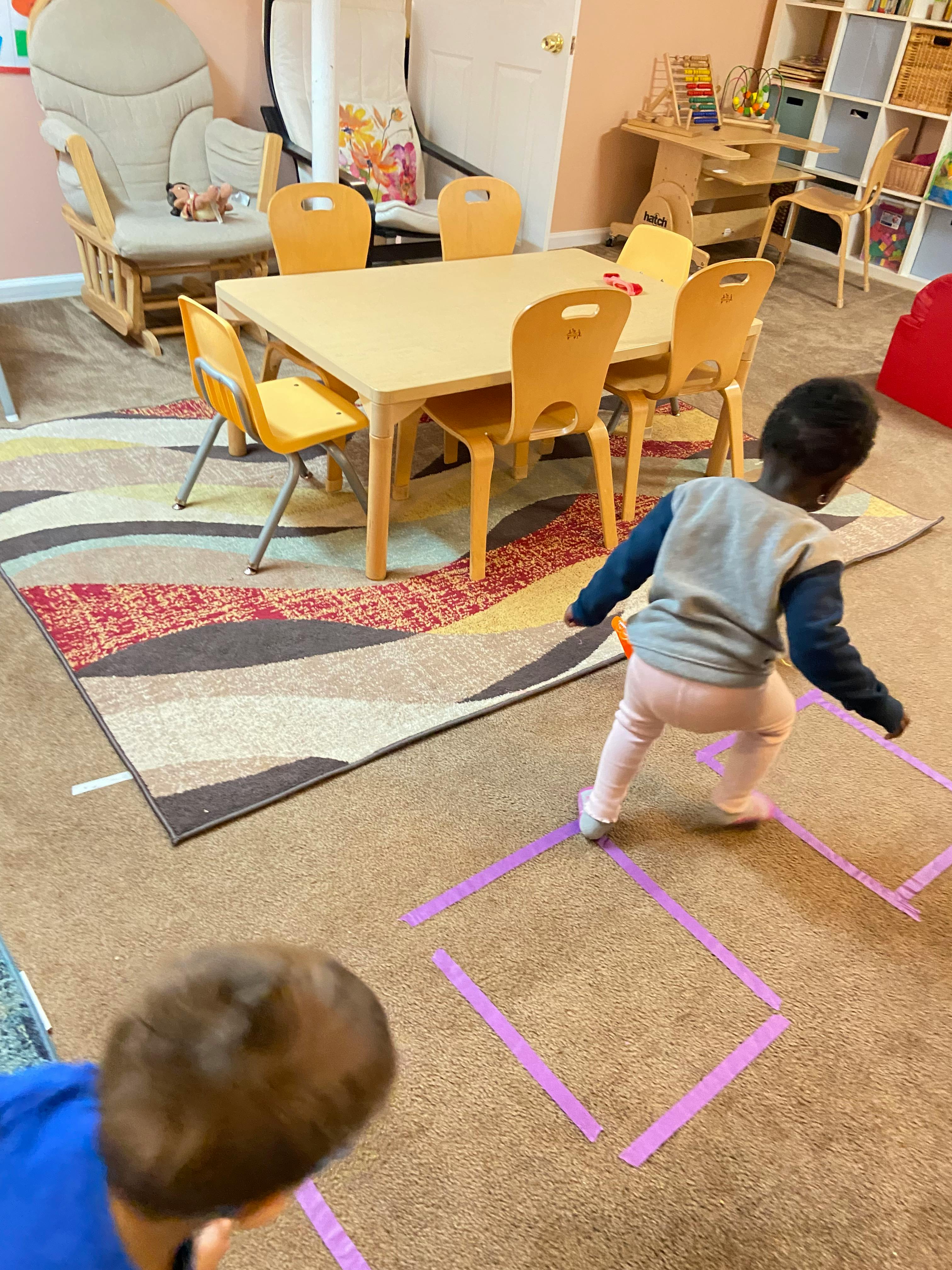 Two children playing on a rug in a classroom
