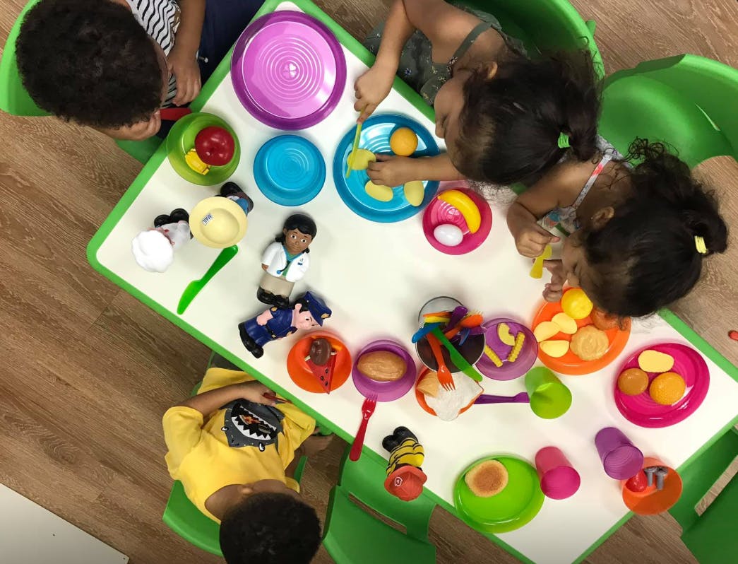 Children playing with toy food and dishes at a table