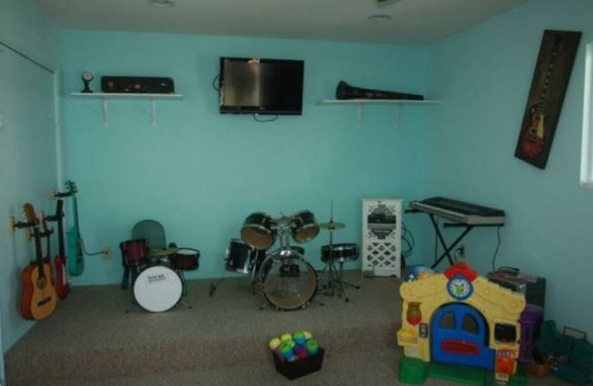 Room with musical instruments including drums, guitars, and a keyboard