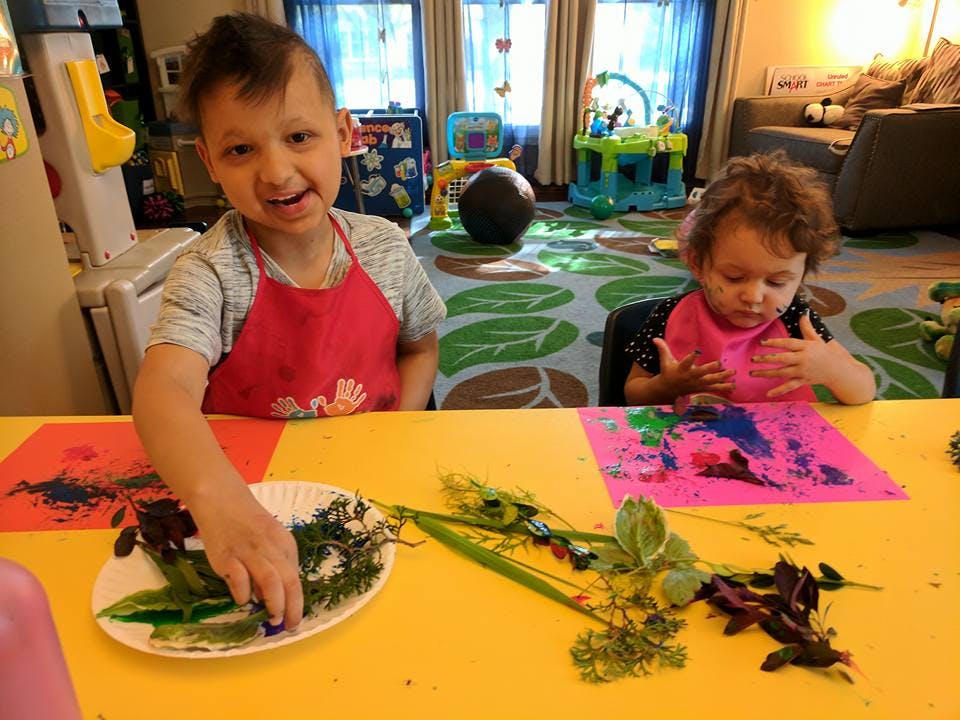 Two children at a table with art supplies and natural elements
