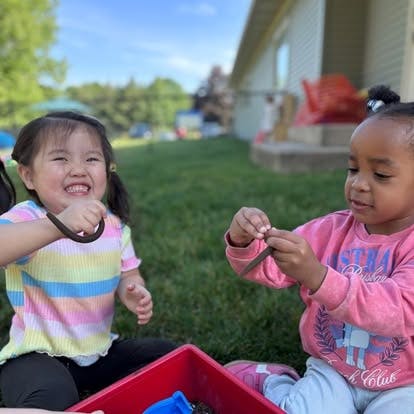 Two children playing with worms outdoors
