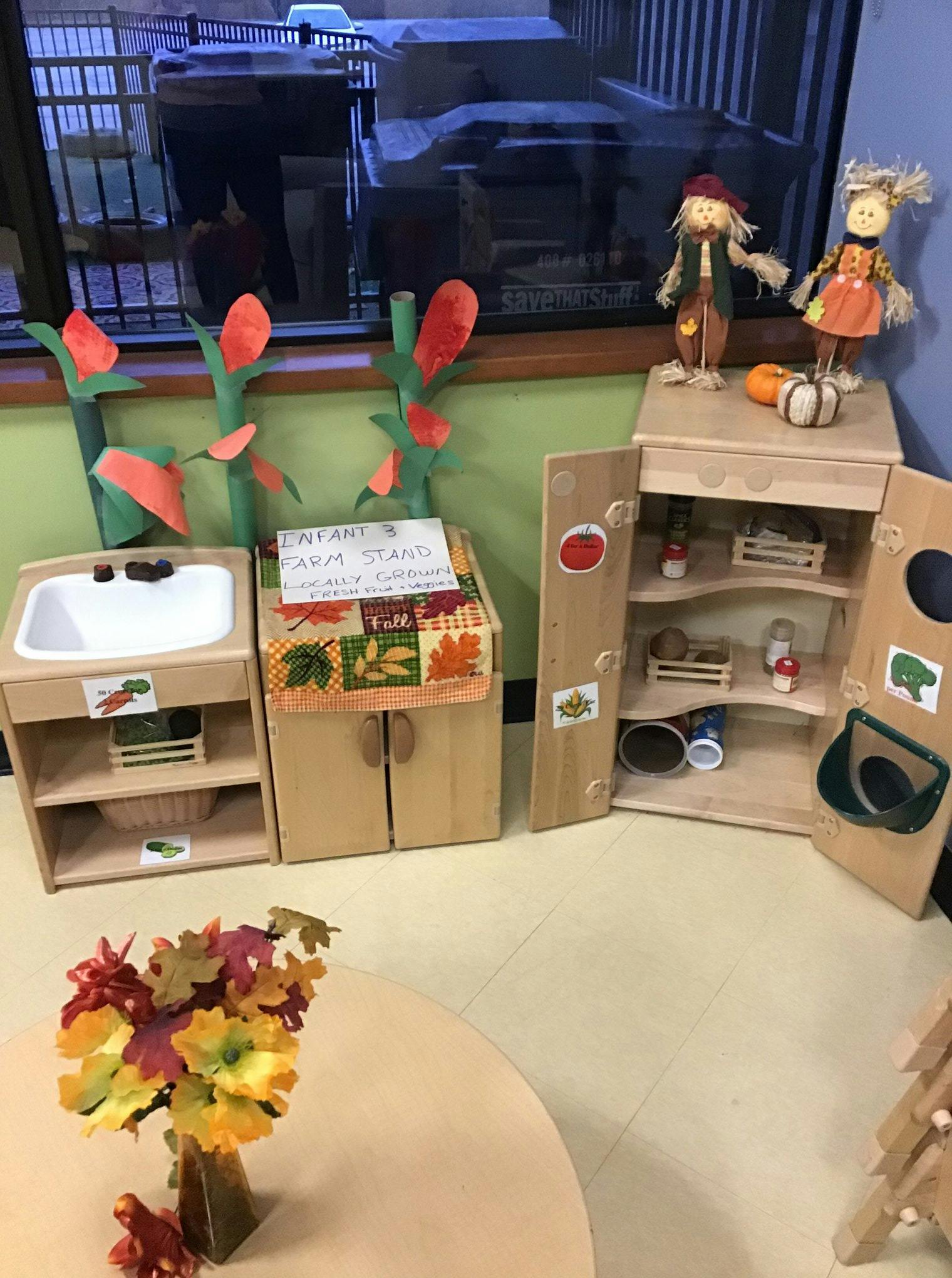 Play kitchen area with sink, cabinets, and scarecrow dolls