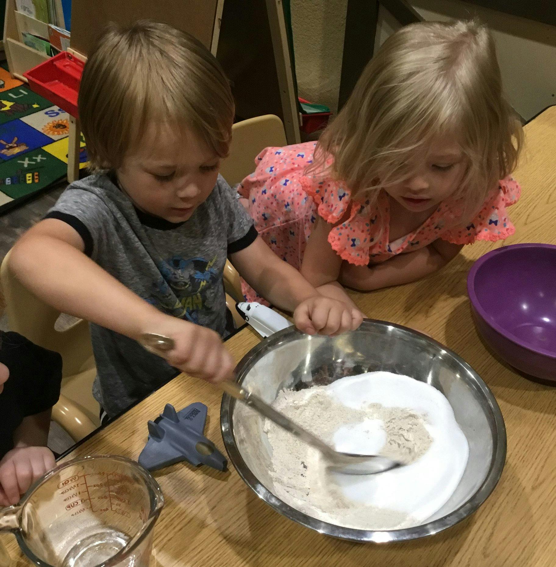 Two children mixing ingredients in a bowl