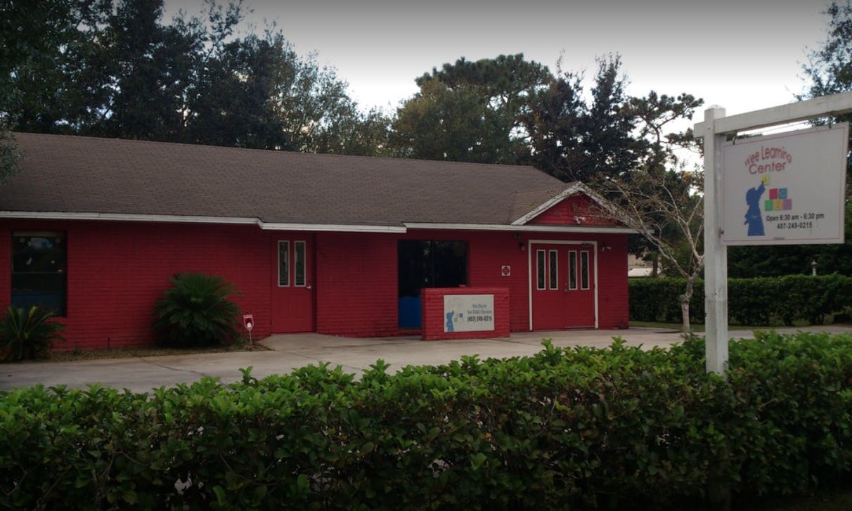 Red building with a brown roof and a sign on a post