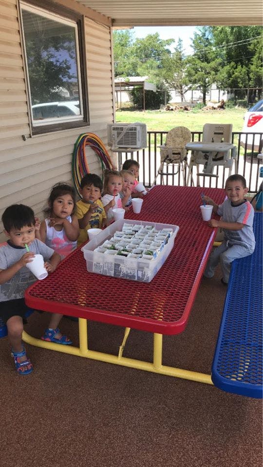 Children sitting at a picnic table with small plant pots