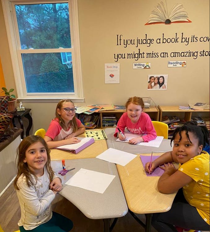 Four children sitting at desks in a classroom