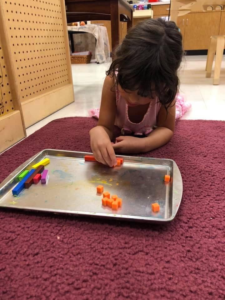 Child on floor playing with colorful blocks on a tray