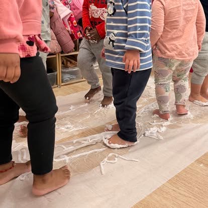 Children walking barefoot in white foam on the floor