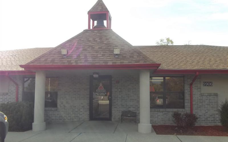 Building with brick facade, a bell tower on the roof, and a door with Kindercare logo