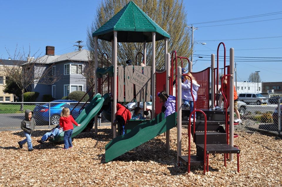 Children playing on a playground structure with slides and climbing structures
