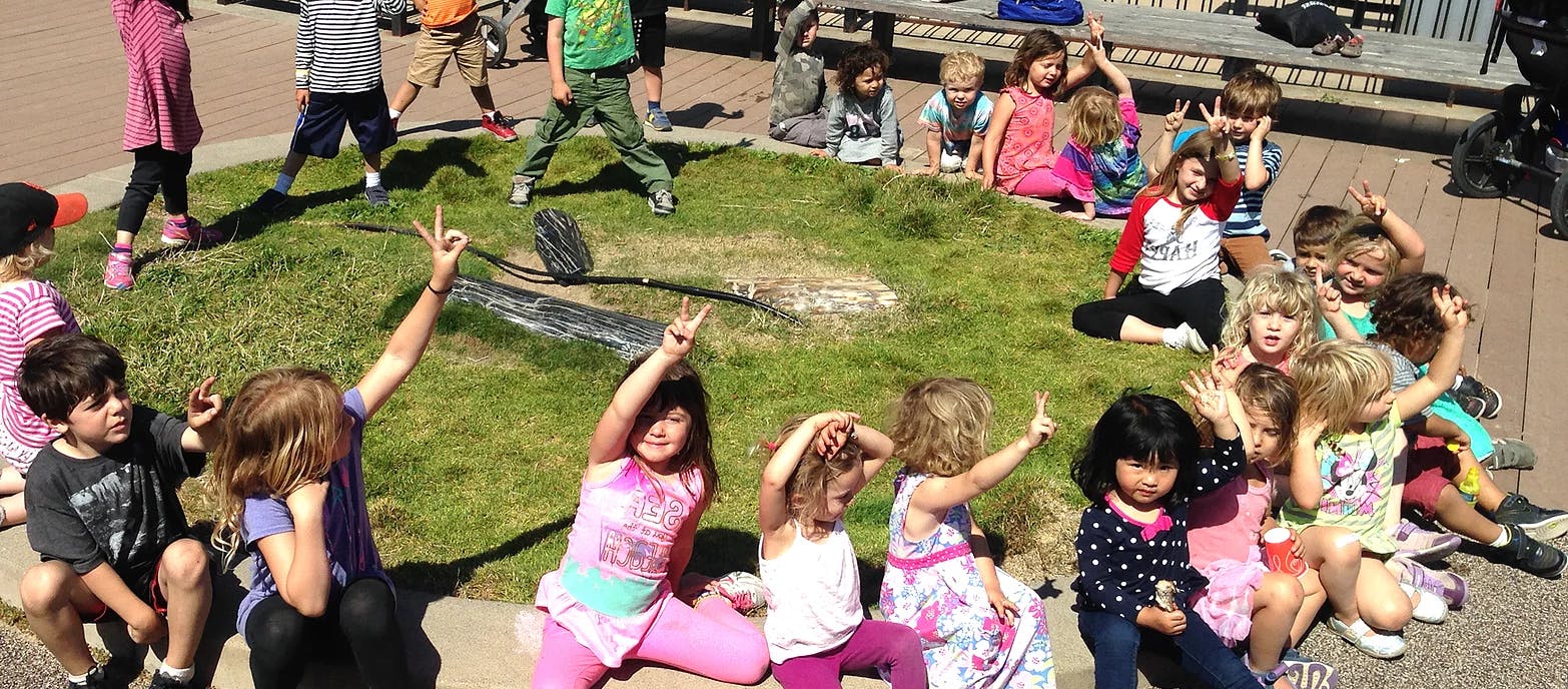Children playing outdoors, some making hand gestures