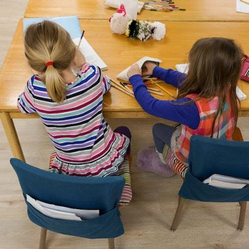 Two children sitting at a table with art supplies