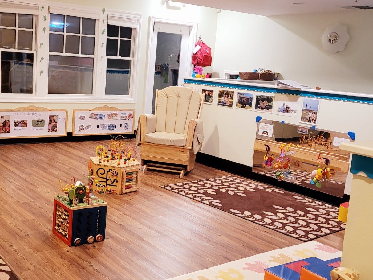Childcare room with a rocking chair, activity cubes, and mirrors with hanging toys