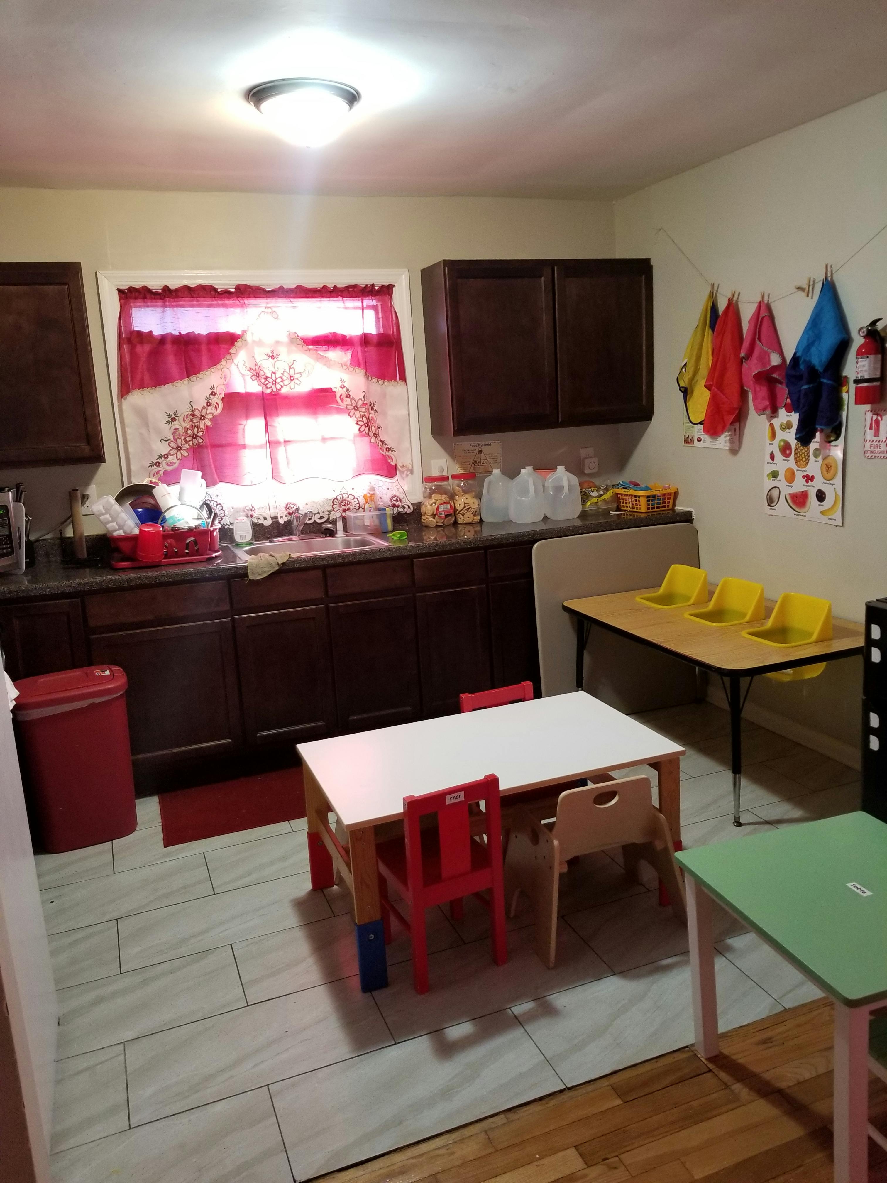 Kitchen with dark cabinets, red curtains, and child-sized tables and chairs