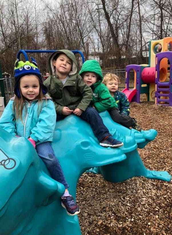 Four children on a blue playground spring rider