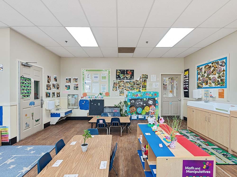 Empty classroom with small tables and chairs, and art on the walls