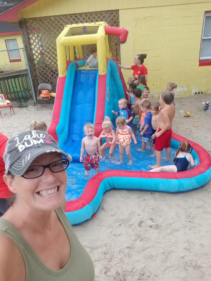 Person in foreground, children playing in an inflatable pool with a slide