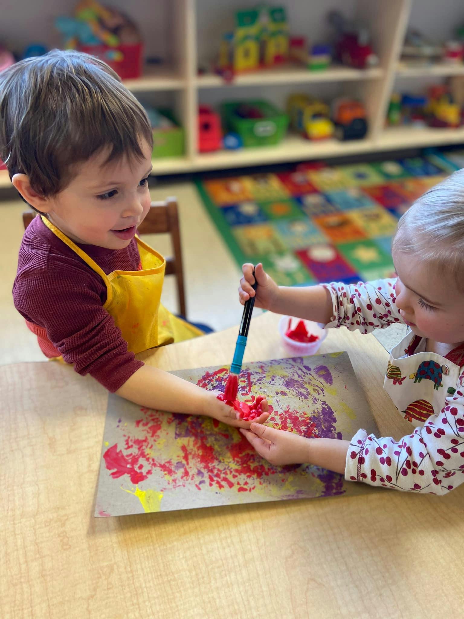 Two children painting on paper at a table