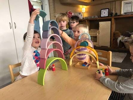 Children playing with colorful arch-shaped blocks on a table