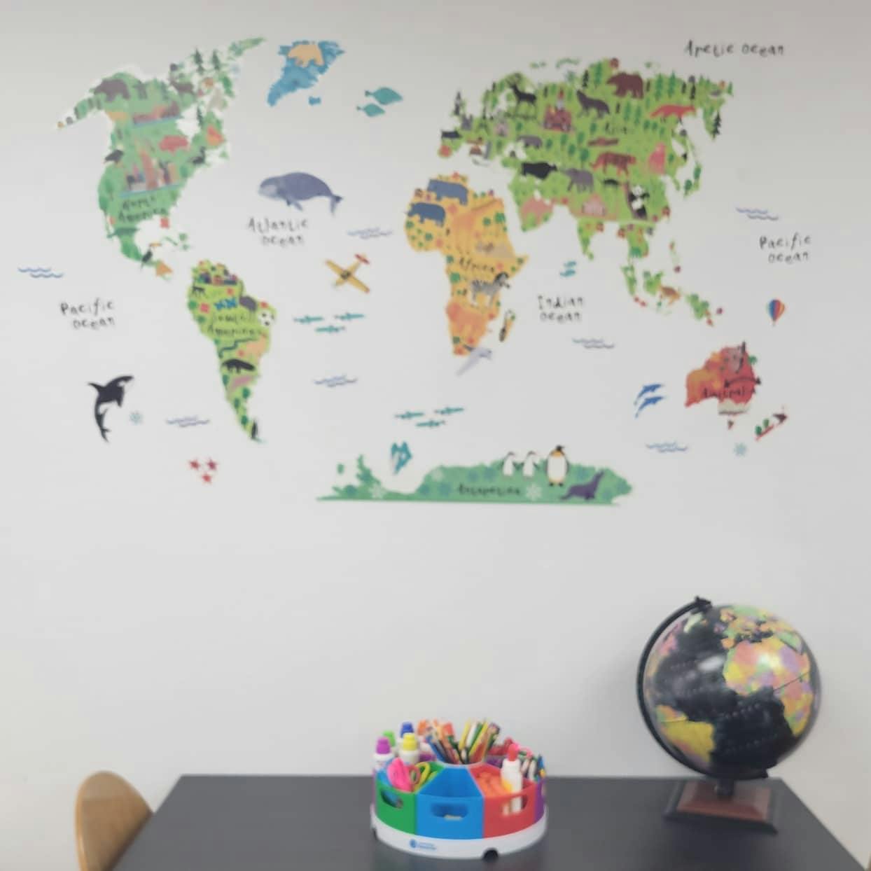 World map wall decal with a globe and art supplies on a table